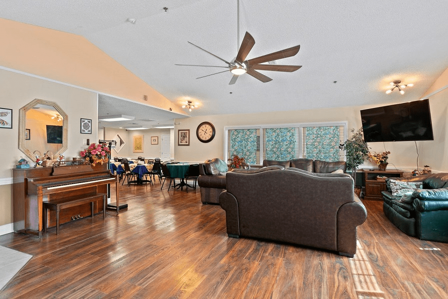 A spacious living room with a ceiling fan, hardwood floors, and comfortable seating.