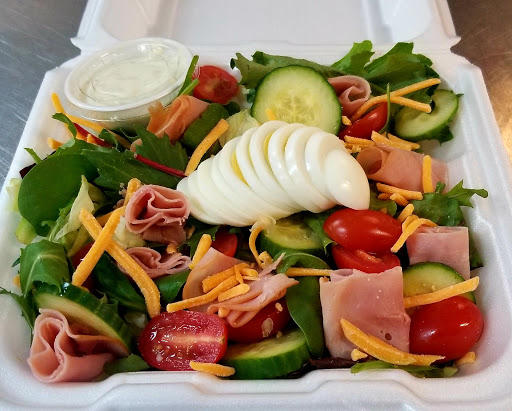 A fresh and colorful salad topped with sliced boiled egg and served with dressing.