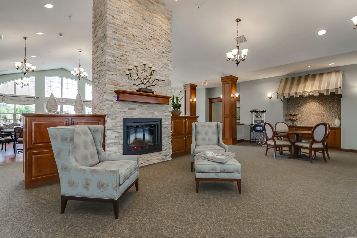 A cozy living room interior featuring a fireplace, elegant seating, and decorative chandeliers.