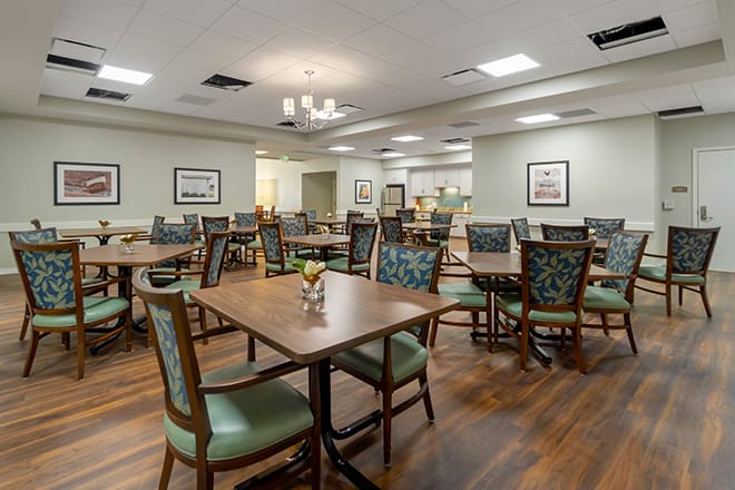 An empty dining room with modern decor and neatly arranged tables and chairs.