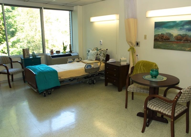 A clean and well-lit hospital room with a bed and seating area.