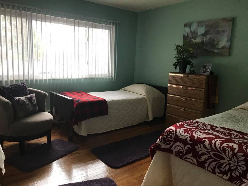 A shared bedroom with two single beds, a window, and comfortable seating.