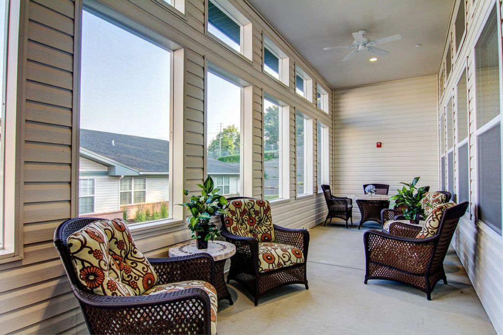 A bright sunroom featuring comfortable seating and large windows allowing natural light.