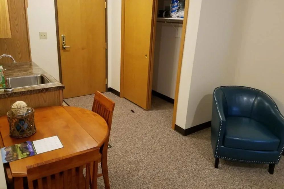 A small office space with a wooden table, chairs, and a blue armchair.