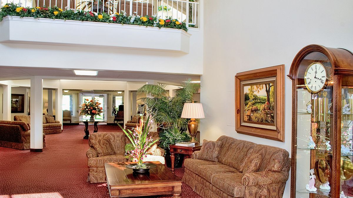 A cozy hotel lobby with comfortable sofas, a coffee table adorned with plants, and artwork on the wall.
