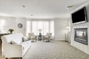 A bright and spacious living room with elegant furnishings, featuring a sofa, chairs, lamps, and a large window with curtains.