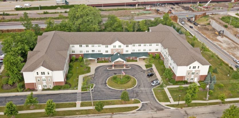 Aerial view of a large building with surrounding greenery and parking lot.