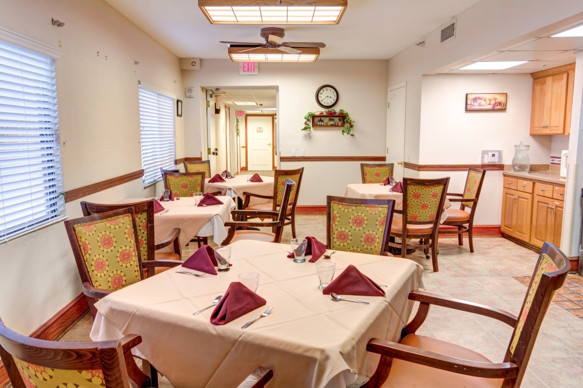 An elegant dining area with neatly arranged tables and chairs, adorned with folded napkins.