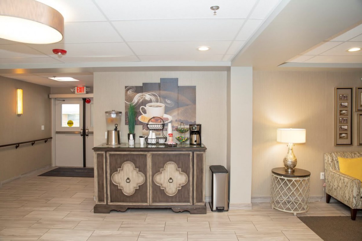 A cozy hotel lobby features a coffee station with various beverages and snacks.