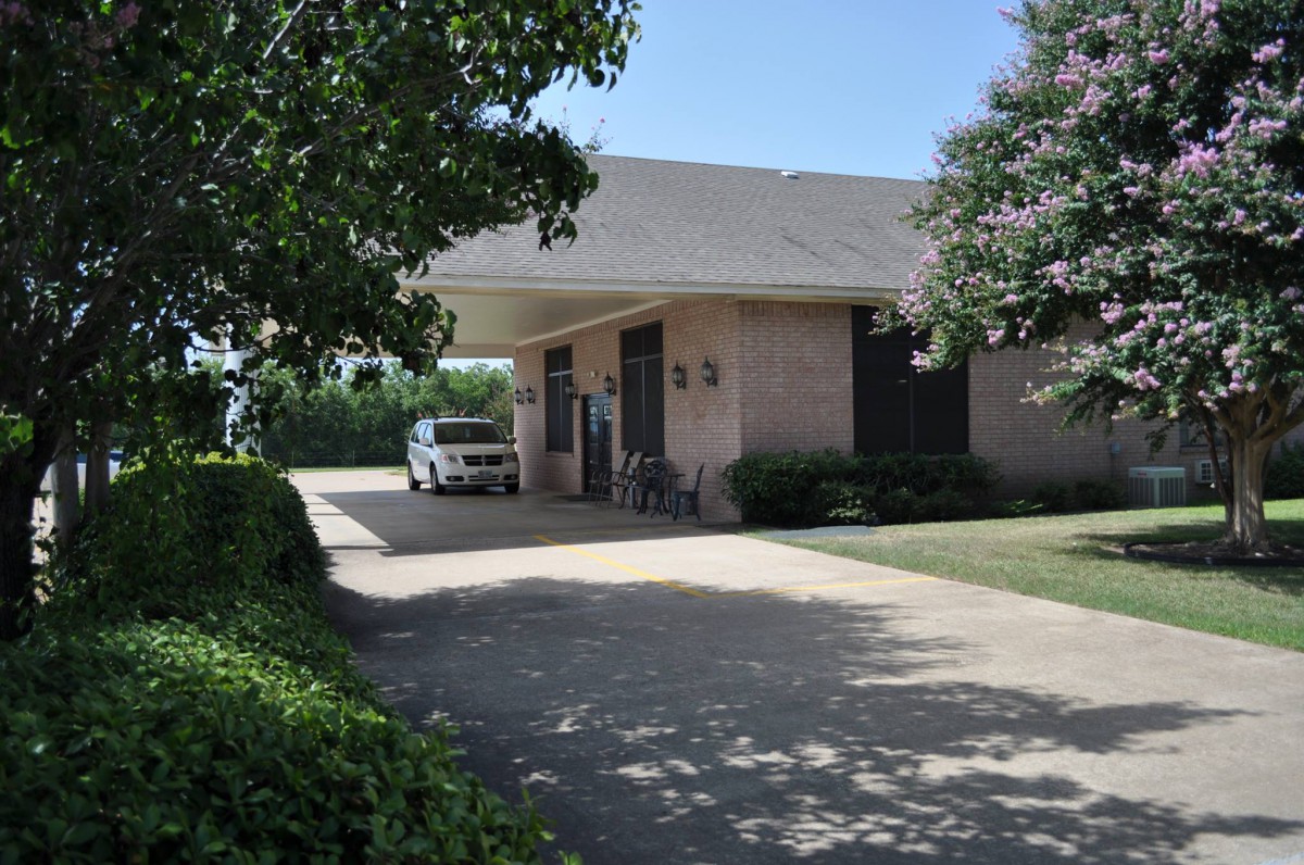 A suburban house with a car parked in the driveway surrounded by trees.