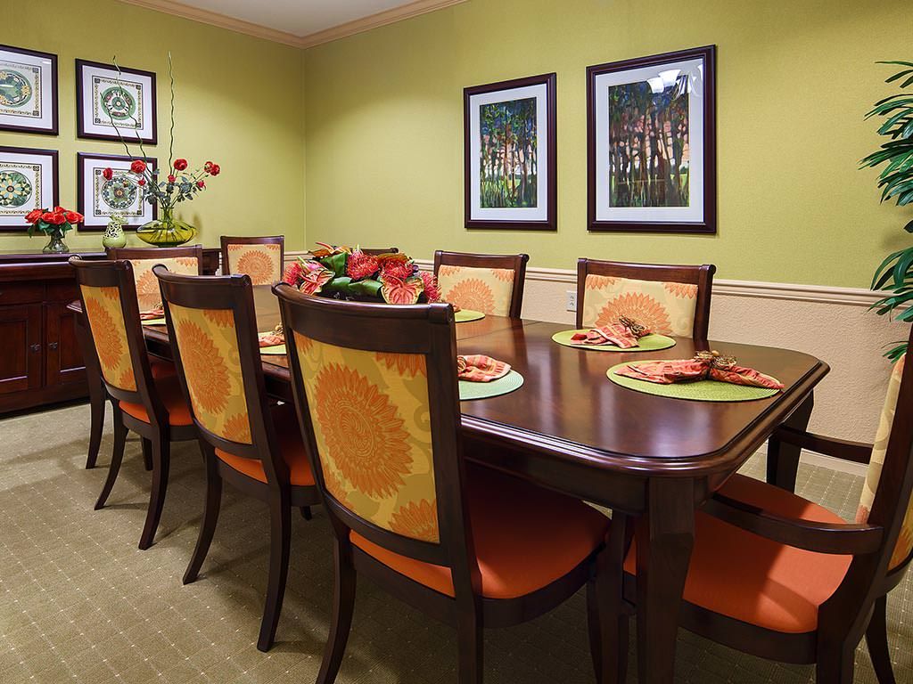 A warmly decorated dining room with a large table and chairs, featuring vibrant artwork on the walls.