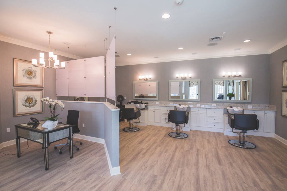 A modern salon interior with stylish chairs, mirrors, and bright lighting.