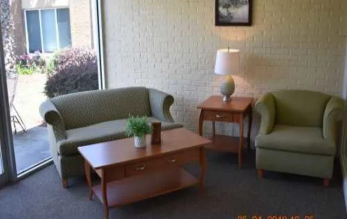 A cozy living room setup featuring a sofa, armchair, coffee table, and lamp.
