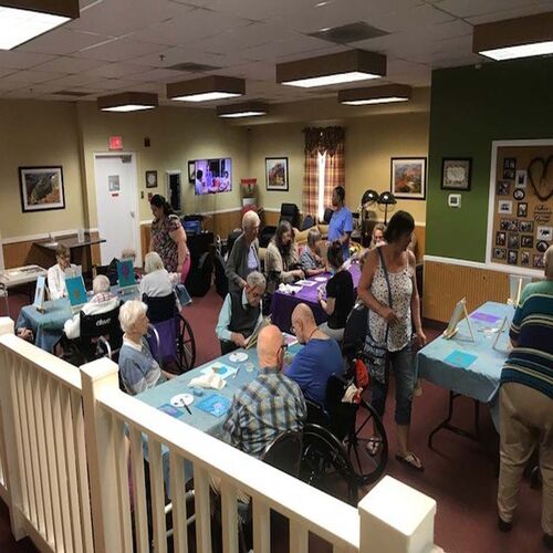 A lively community gathering at a senior center with residents and caregivers engaging in activities.