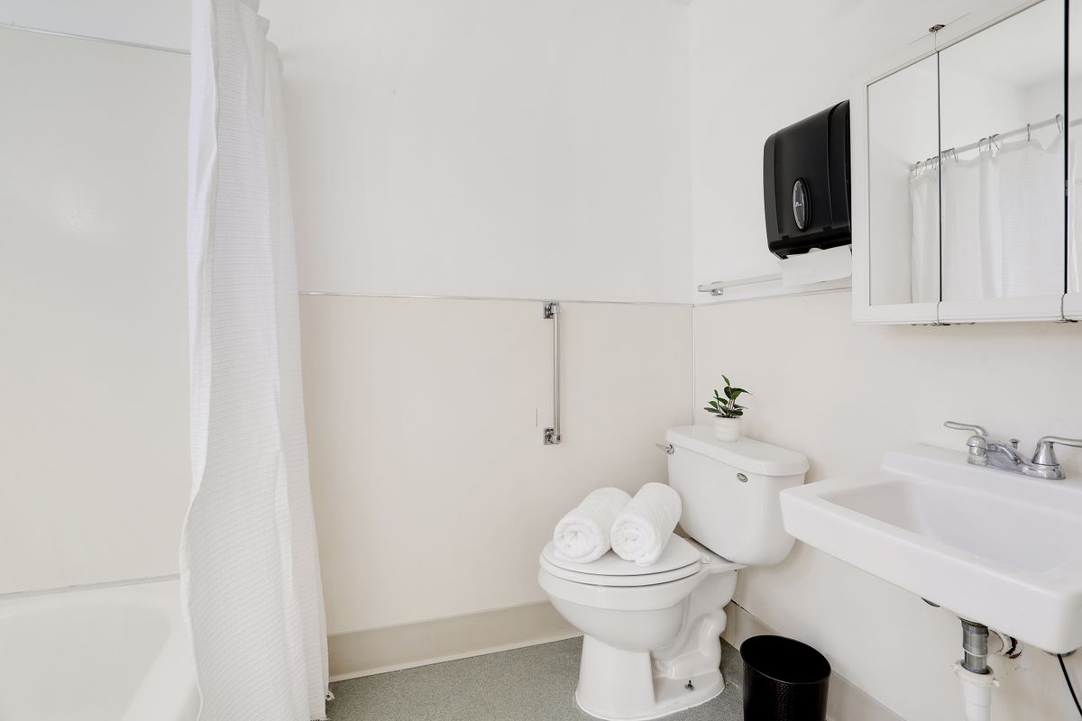 A clean and minimalistic bathroom with a toilet, sink, and white shower curtain.