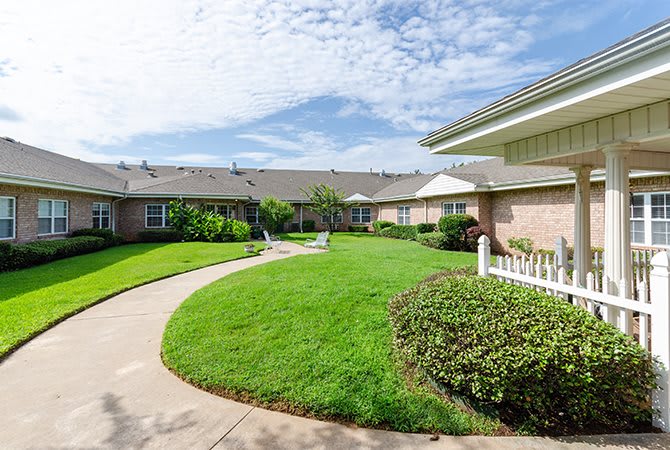 A well-maintained garden with a winding pathway in a residential area under a cloudy sky.