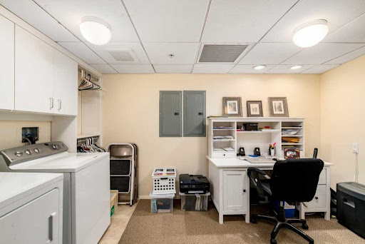 A neatly organized home office space featuring a desk and laundry area.
