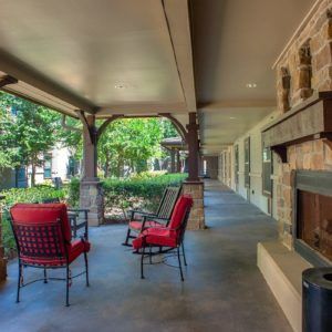 A cozy outdoor porch with seating and a fireplace, overlooking a garden.