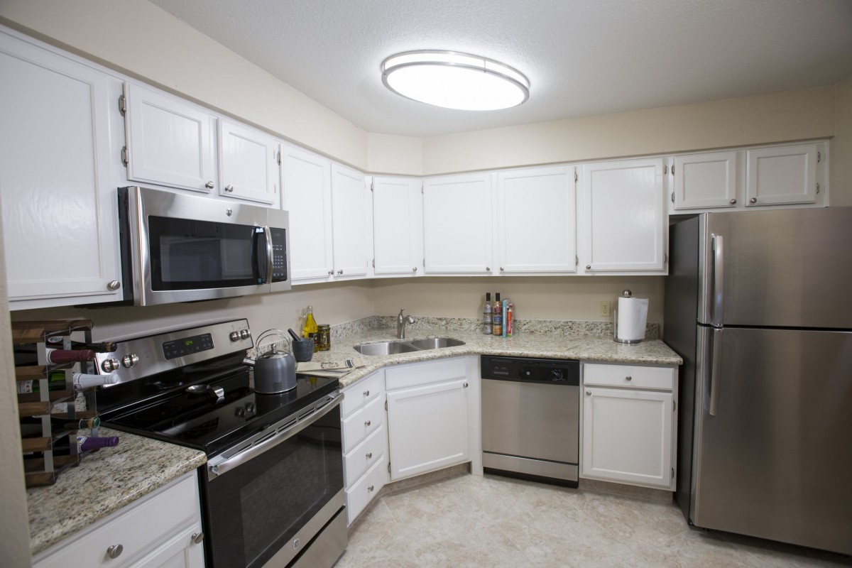 A modern kitchen with white cabinets and stainless steel appliances.