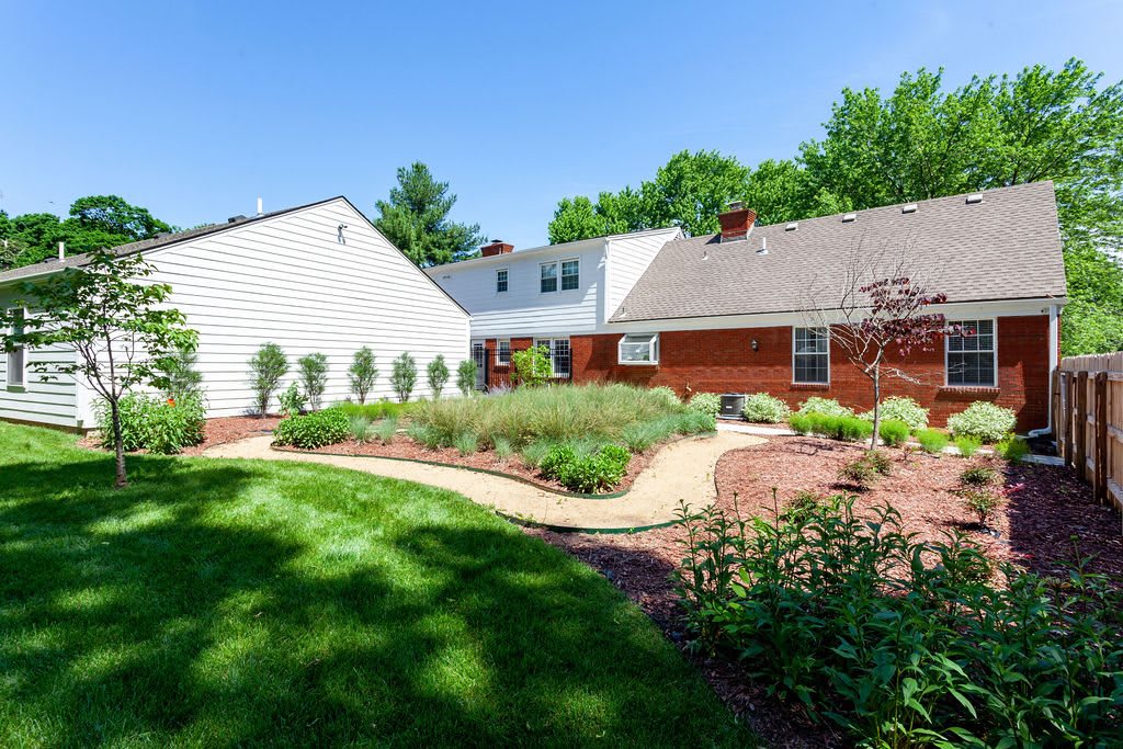 A well-maintained backyard featuring a garden with bushes and a neatly trimmed lawn.