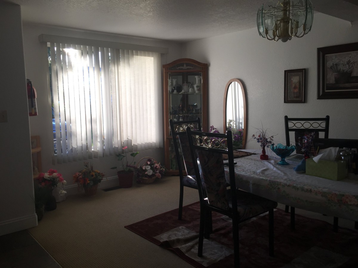 A dining room featuring a table with chairs, a china cabinet, and a mirror by the window.