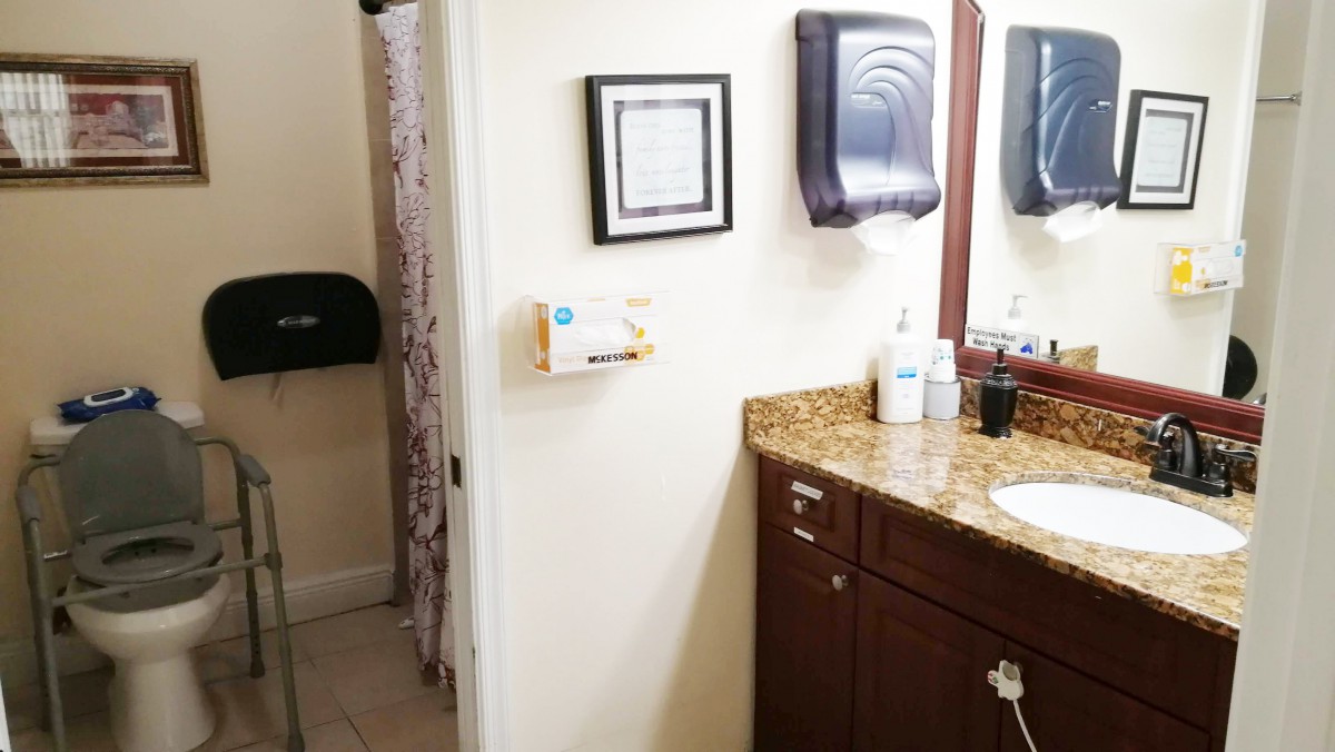 A clean and tidy bathroom with a granite countertop, sink, mirror, and various dispensers.