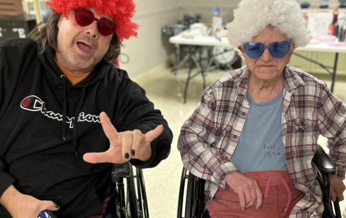 Two people in colorful wigs and sunglasses enjoying a fun event indoors.