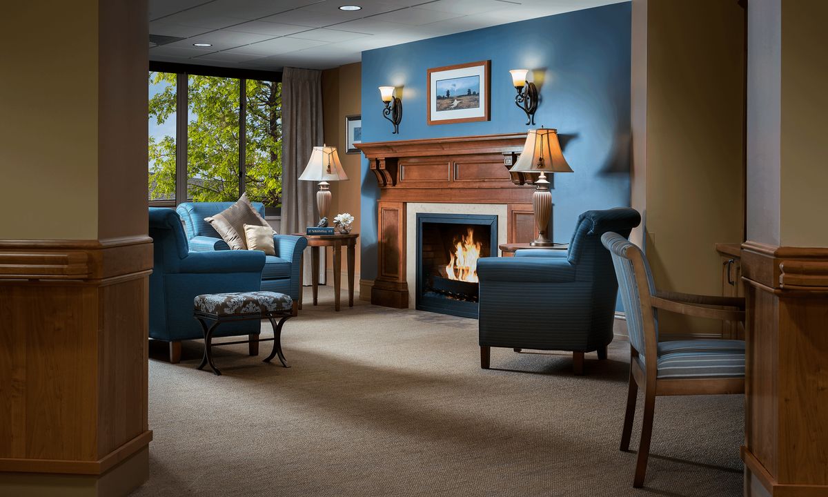 A cozy living room with blue walls, featuring a warm fireplace and comfortable armchairs.