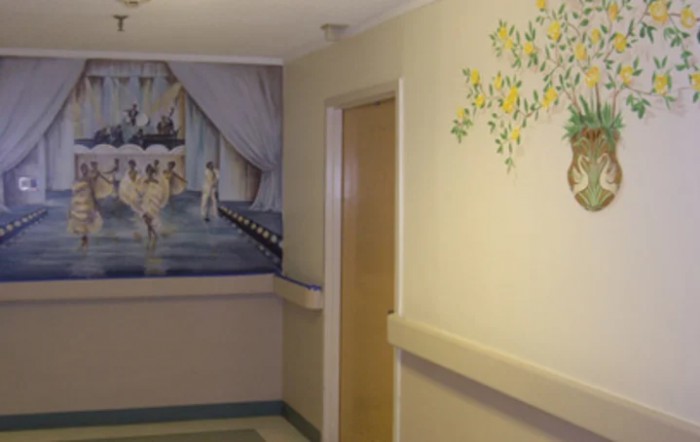 A hospital hallway with decorative murals on the walls.