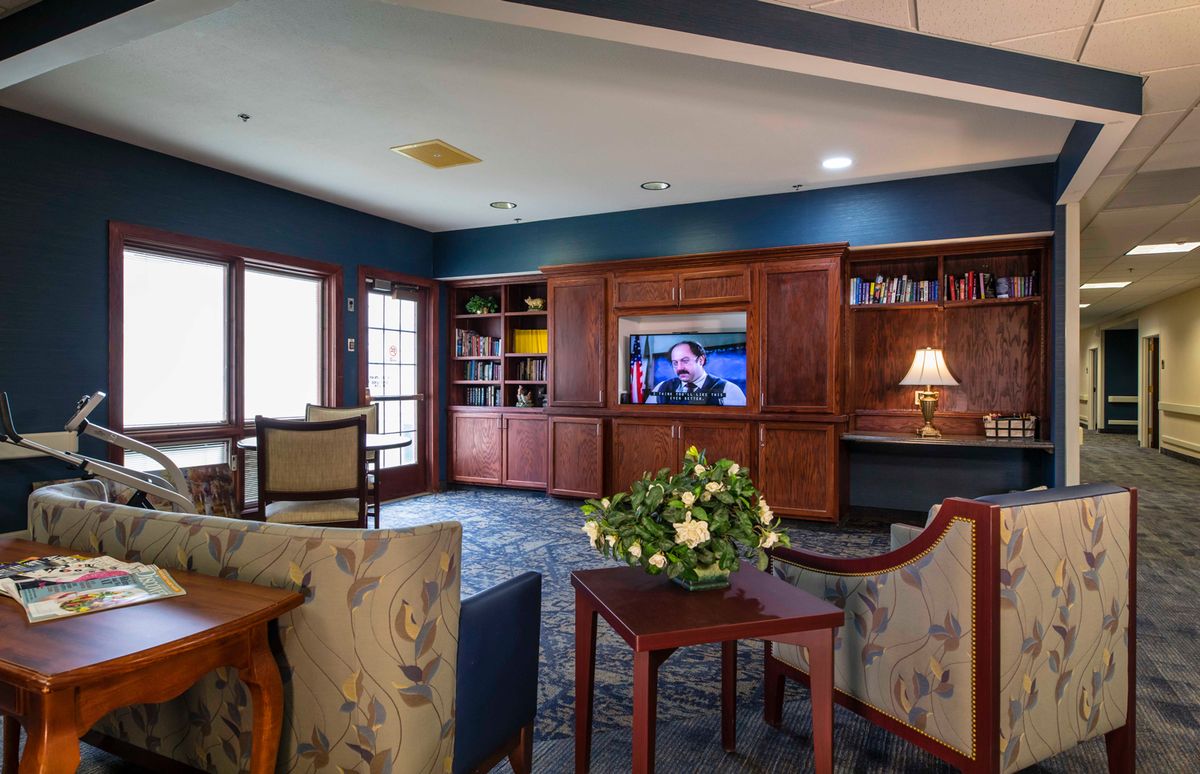 A cozy living room with a television, bookshelves, and comfortable seating.