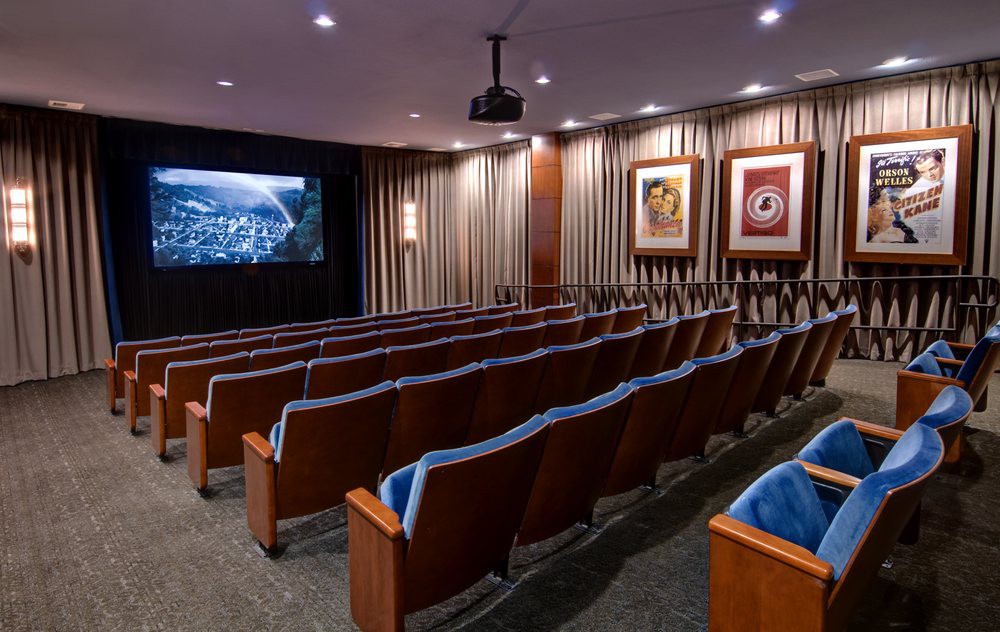 A cozy home theater with rows of comfortable seating and a large projection screen.