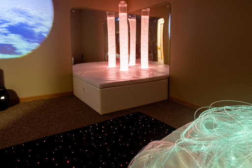 A serene therapeutic space featuring illuminated columns and a cozy seating area, designed for relaxation and sensory experiences.