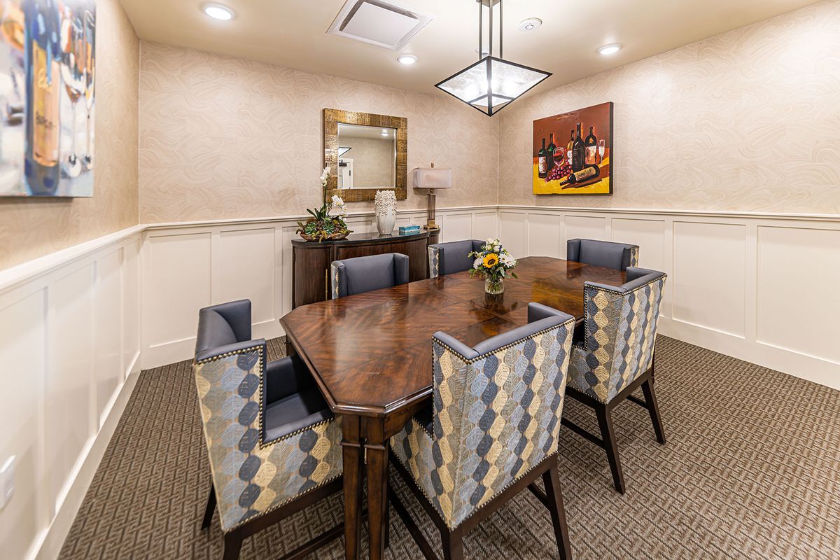A stylish dining room featuring a wooden table, patterned chairs, and decorative elements including a mirror and artwork on the wall.