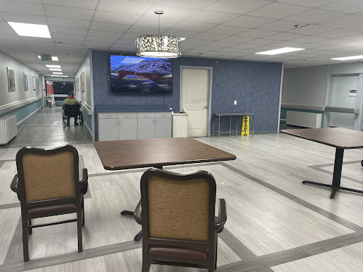 A spacious indoor area featuring a table, chairs, and a television on the wall.