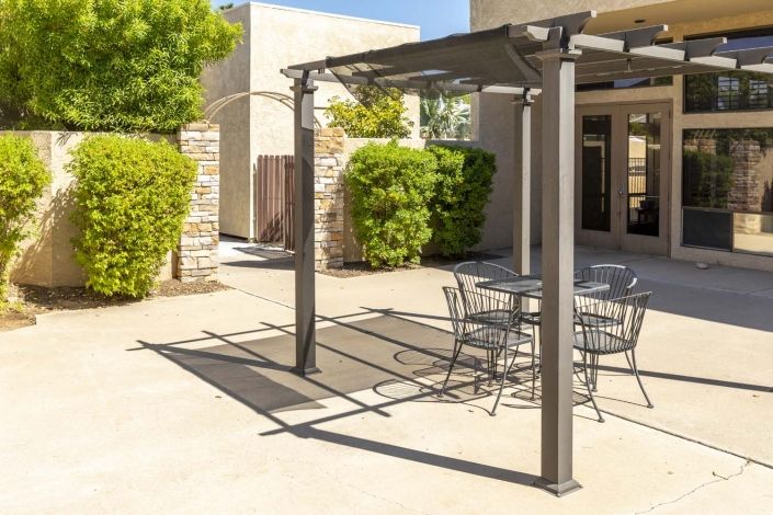 A sunny outdoor patio featuring a modern pergola and metal seating area.
