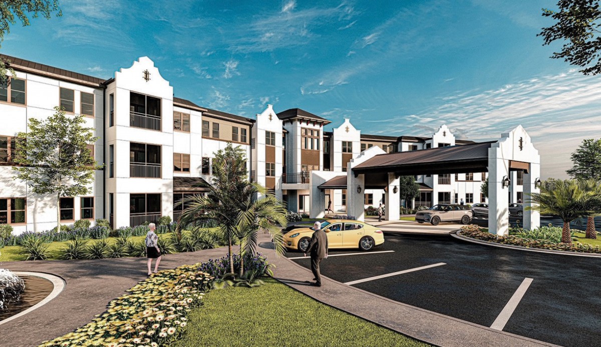 Modern residential building with landscaping and parked cars on a sunny day.