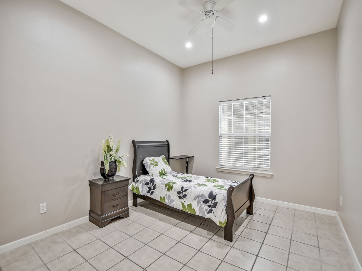 A minimalist bedroom with a single bed, nightstand, and tile flooring.