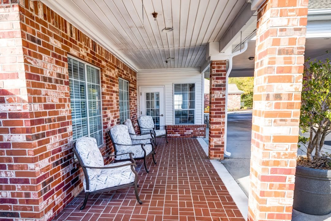 A brick porch with comfortable outdoor chairs, offering a cozy space for relaxation.