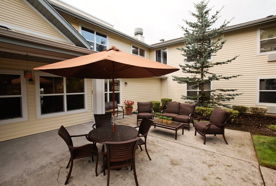 A cozy backyard patio with a table, chairs, and an umbrella.
