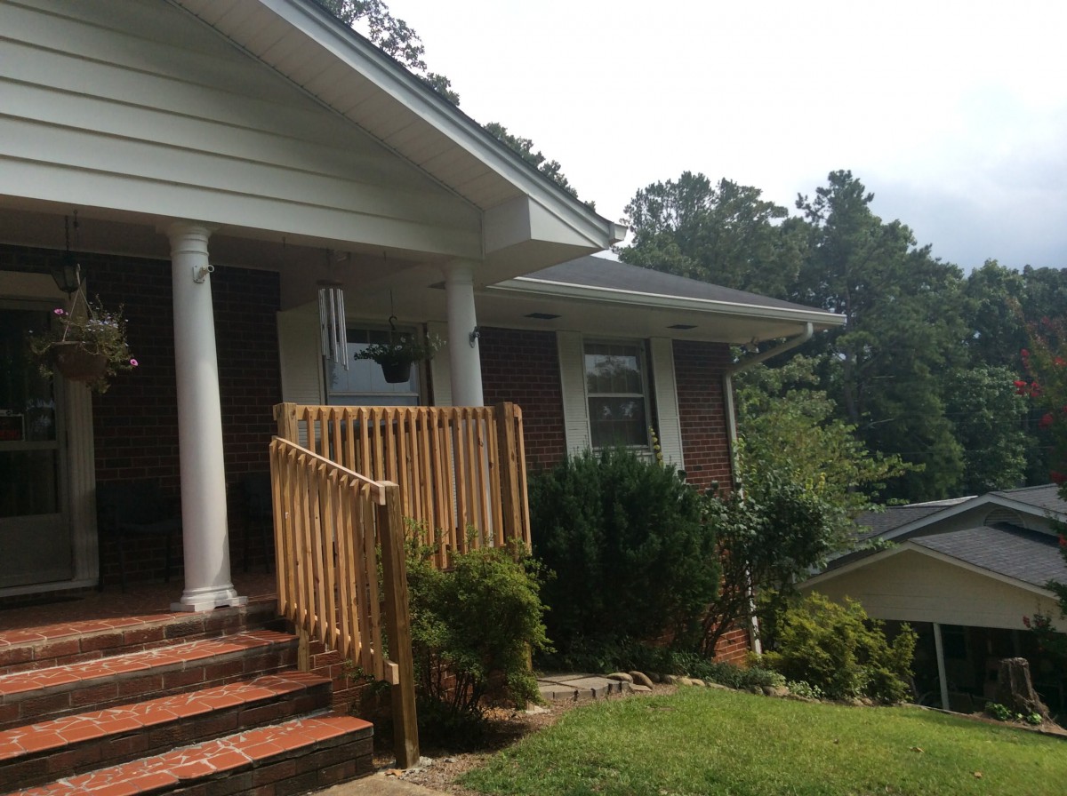 A brick house with a porch featuring columns and a small front yard.