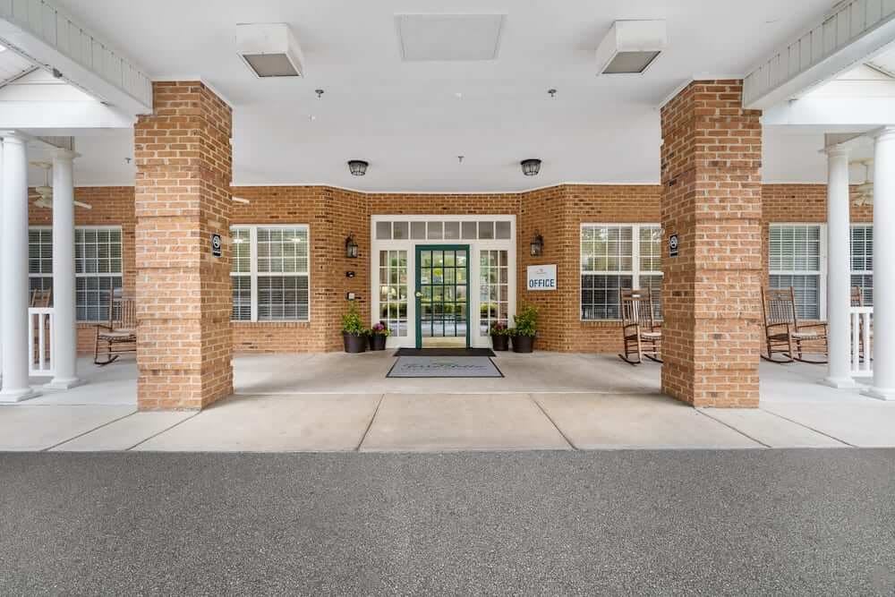 A brick building entrance with columns and large windows.