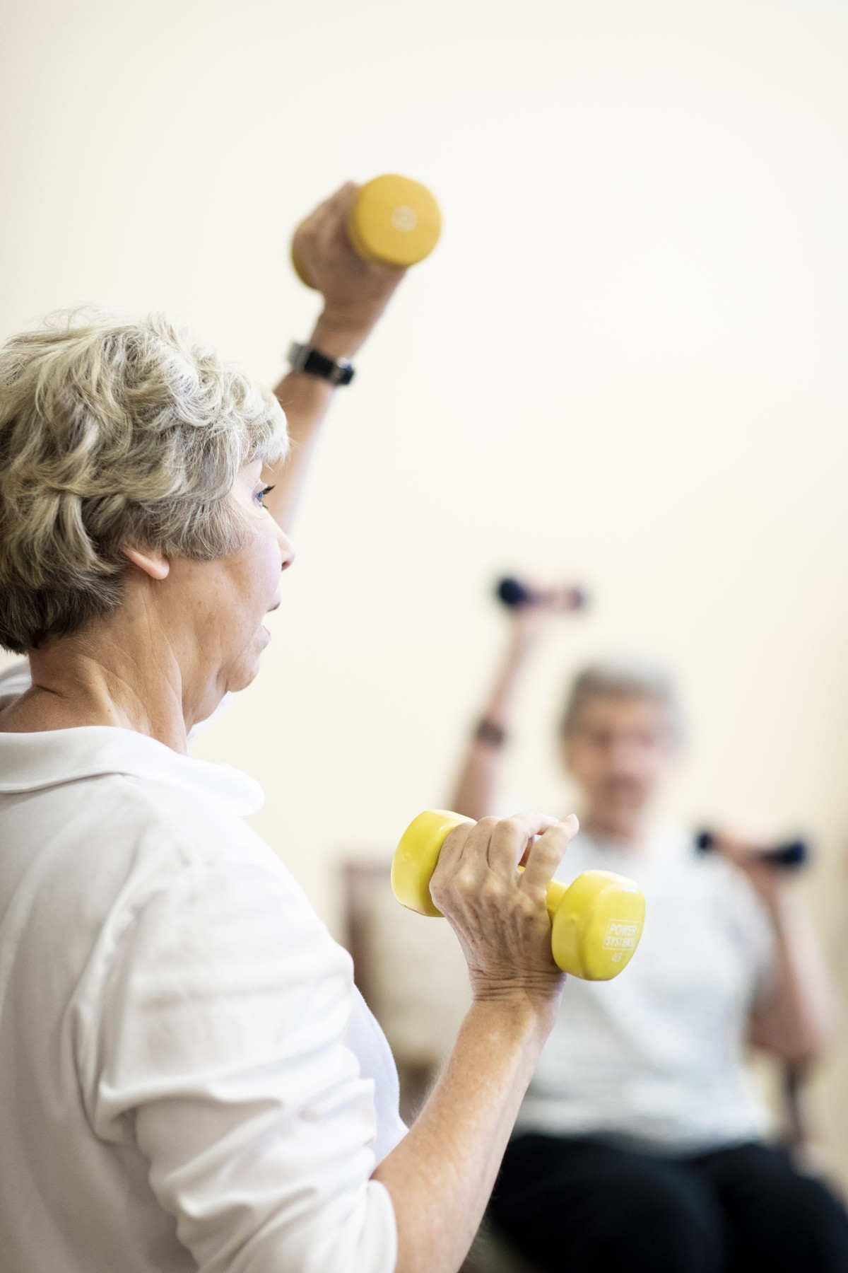 Elderly individuals participating in a strength training exercise class with dumbbells.