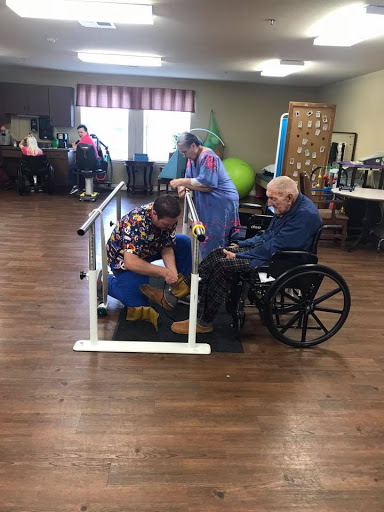 A scene from a rehabilitation facility where seniors engage in physical therapy exercises with assistance.