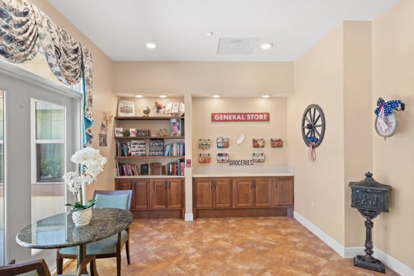 A cozy reading nook with a bookshelf, table, and decorative wall clock.