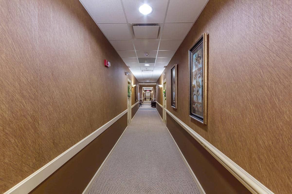 A well-lit hallway with artwork on the walls and a carpeted floor.