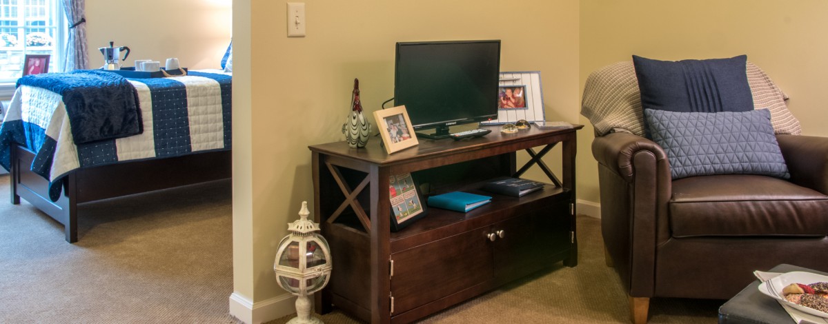 A wooden entertainment unit with a television, framed photo, decorative items, and books.