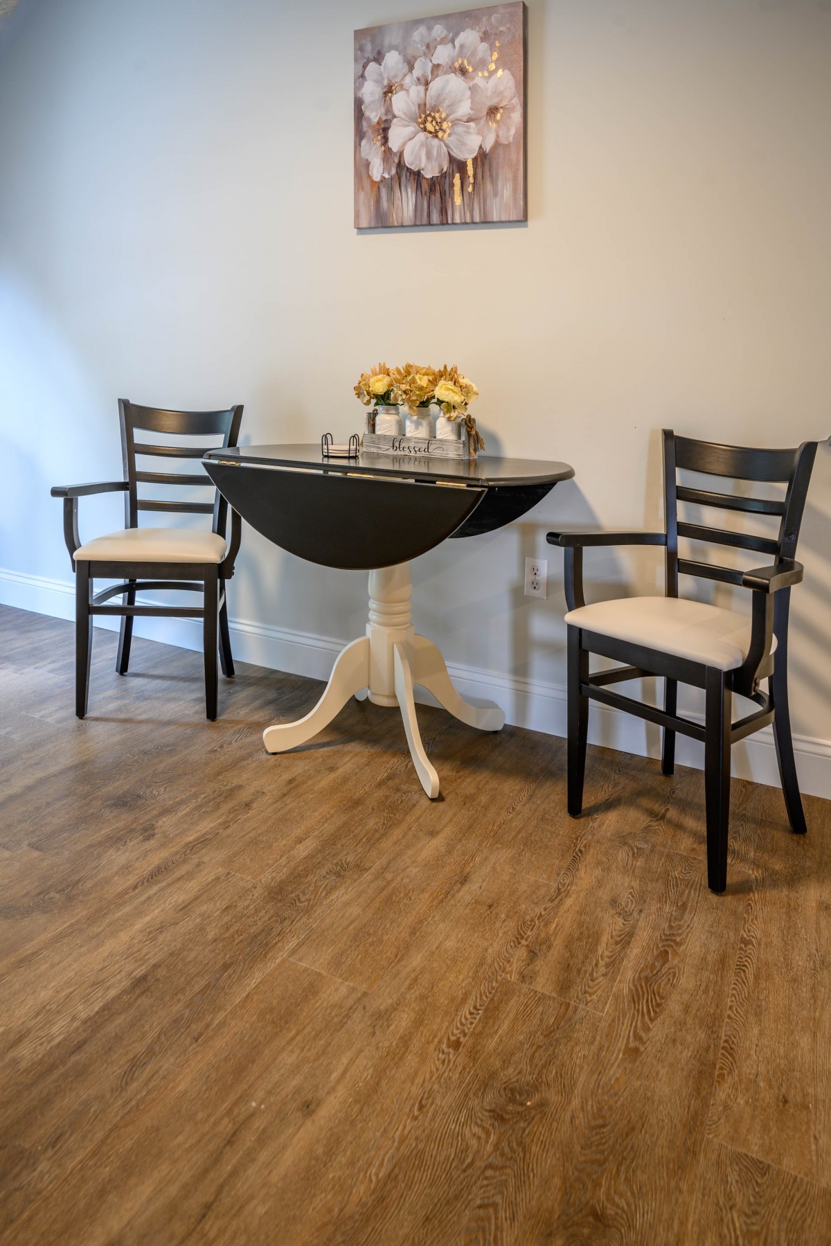 A cozy dining area with two chairs and a small round table on a wooden floor.