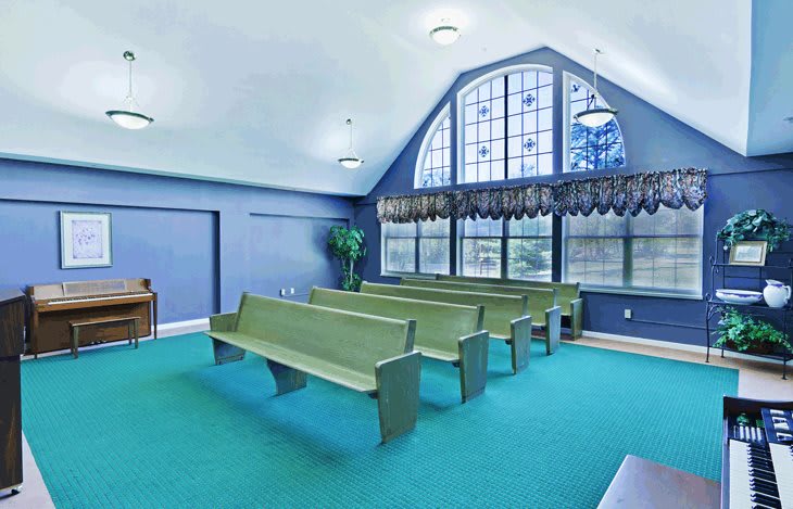 Interior view of a chapel with pews and large windows.
