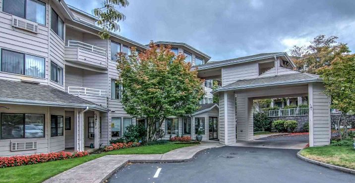 A residential building with a landscaped entrance and a cloudy sky overhead.