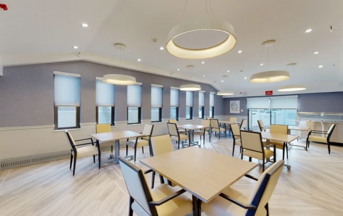 A modern dining area with multiple tables and chairs, featuring contemporary lighting.